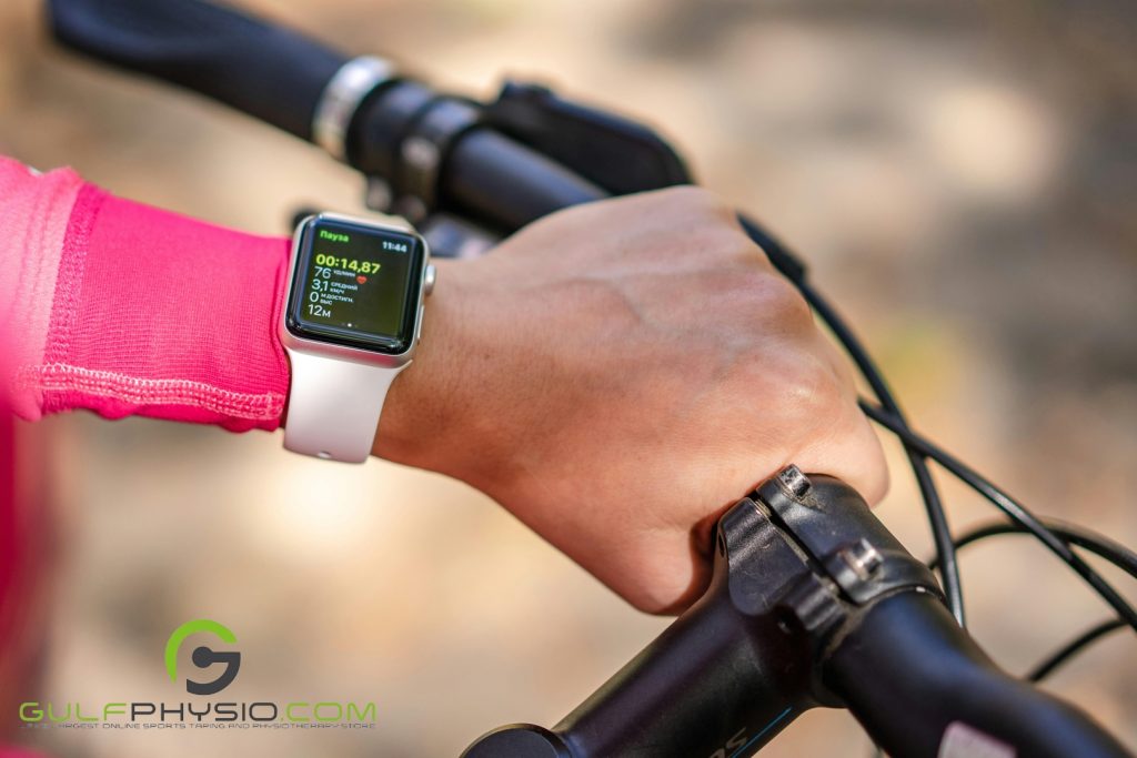 A close-up photo of a cyclist’s wrist wearing a smartwatch. The smartwatch is displaying data from her exercise.