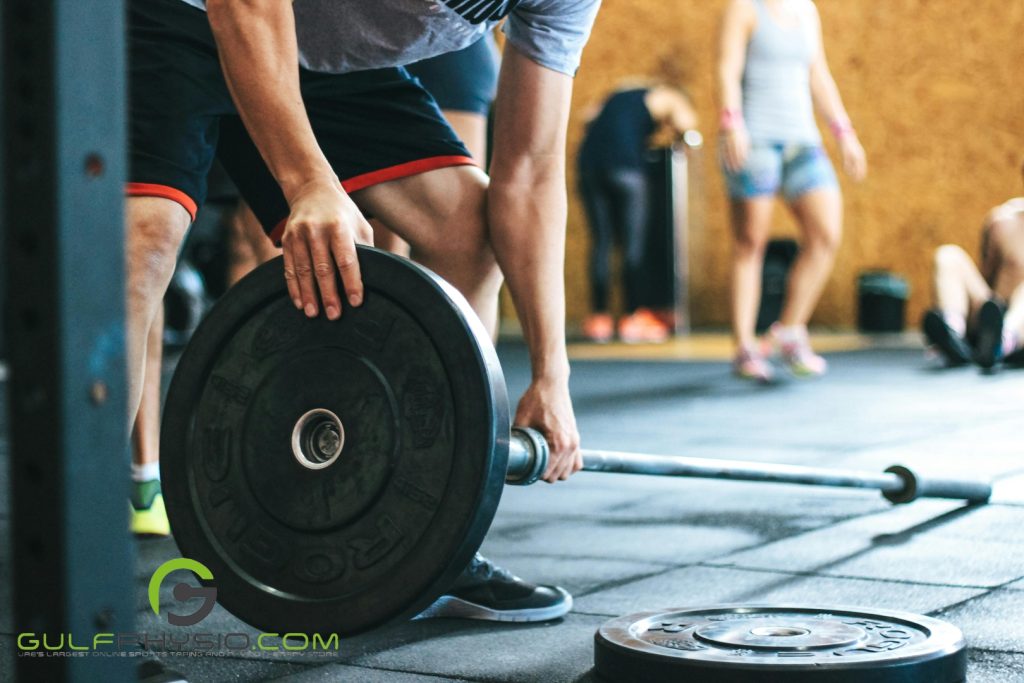 A close-up photo of a person placing plates onto a weight training bar.