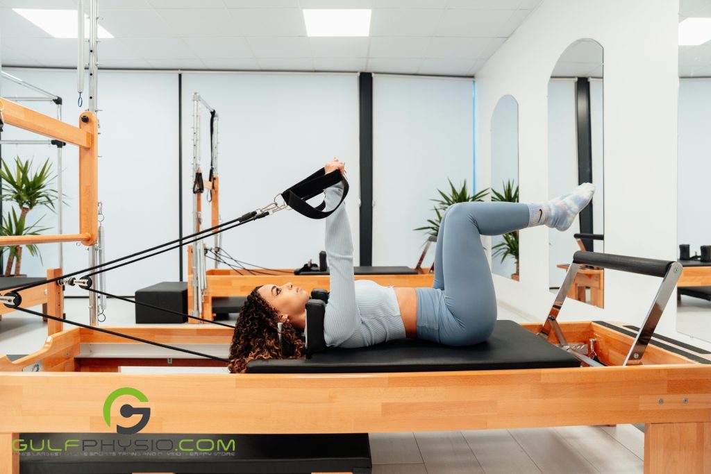 A woman working out on a Pilates reformer.