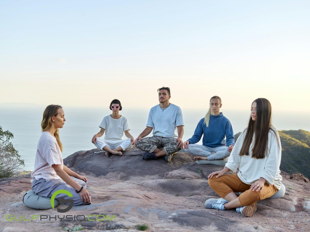 A group of young adults are meditating on a mountainside.