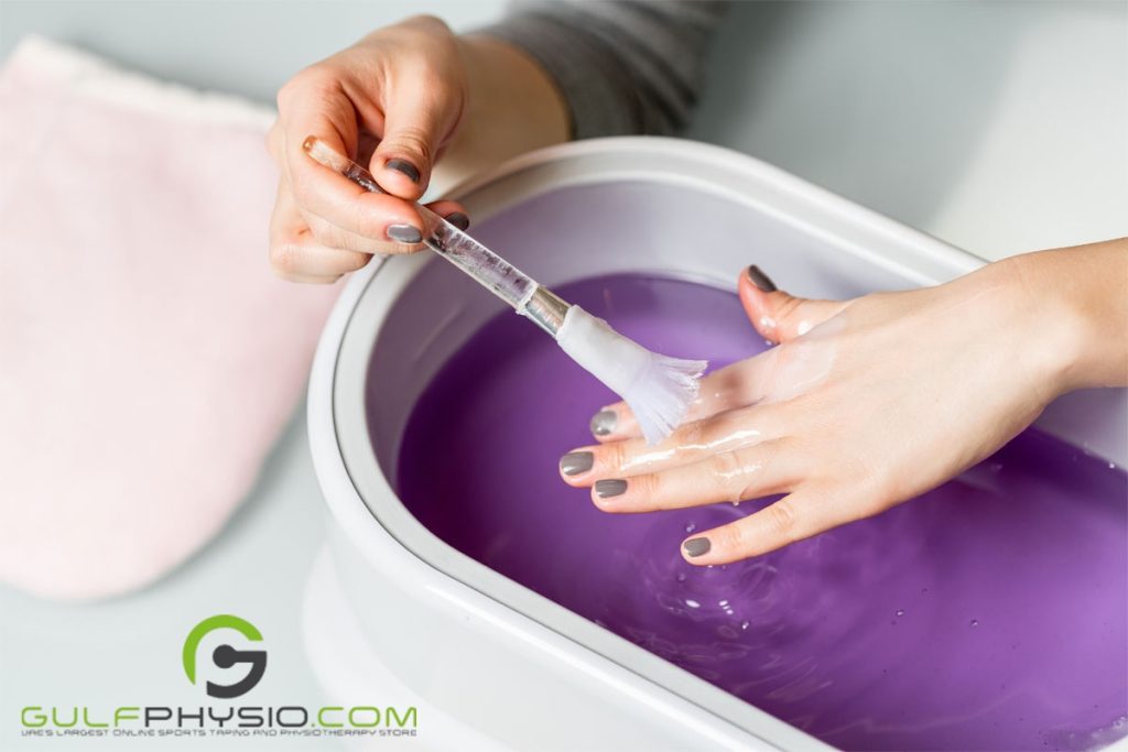 A person brushing some melted paraffin wax over their own hand