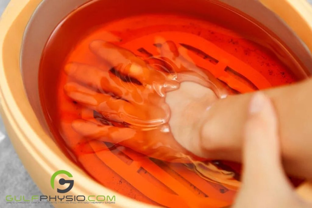 A hand is submerged in a warm paraffin wax therapy bath