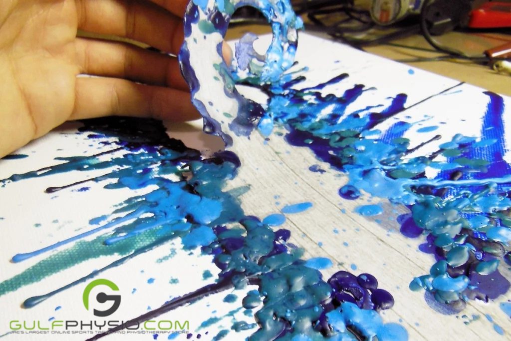 A person shaving off layers of the materials with blue paraffin wax on the encaustic art