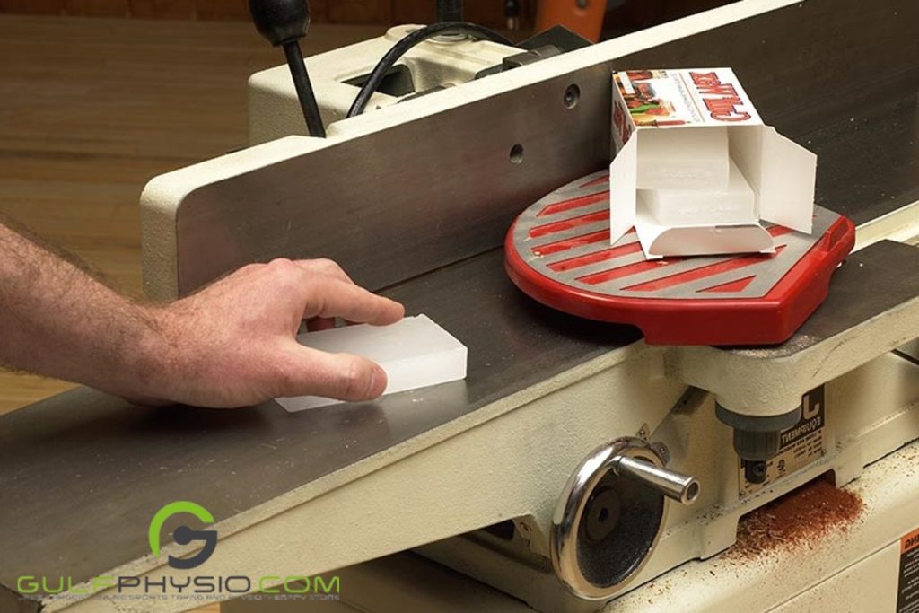 A person putting paraffin wax on a metal worktable