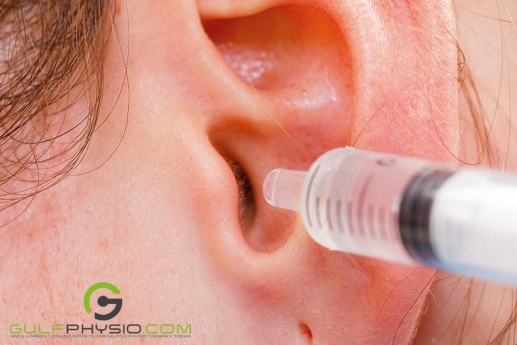 An ear is getting a couple drops of paraffin wax through a syringe to remove excess earwax