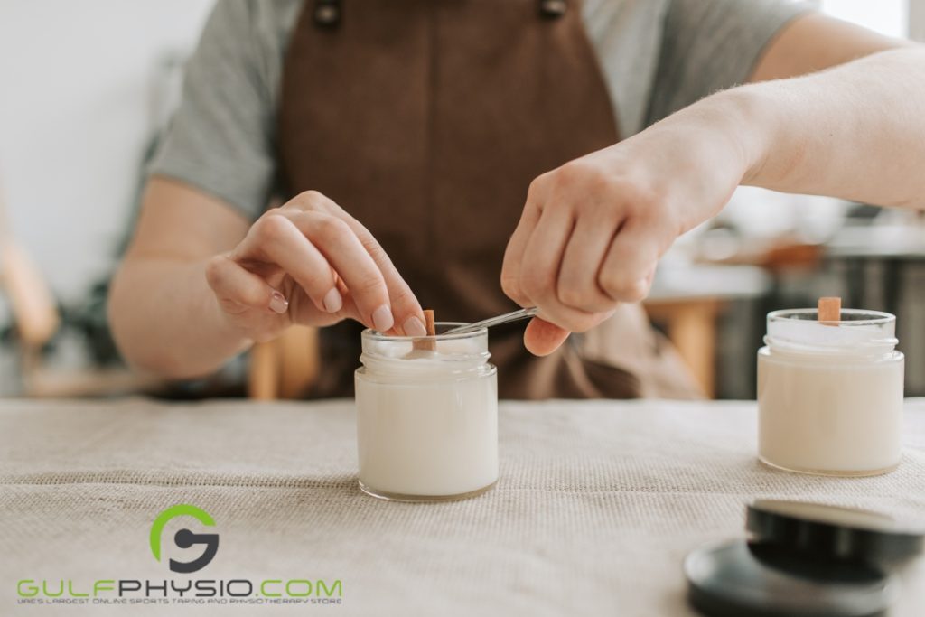 A person is cutting the wick of a newly-poured paraffin wax candle on a table