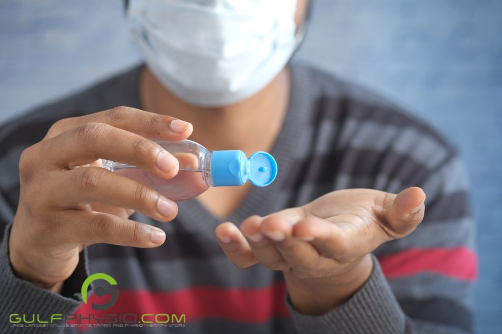 A person is putting on rubbing alcohol on their hand, holding up the clear bottle with a blue cap