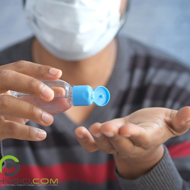 A person is putting on rubbing alcohol on their hand, holding up the clear bottle with a blue cap