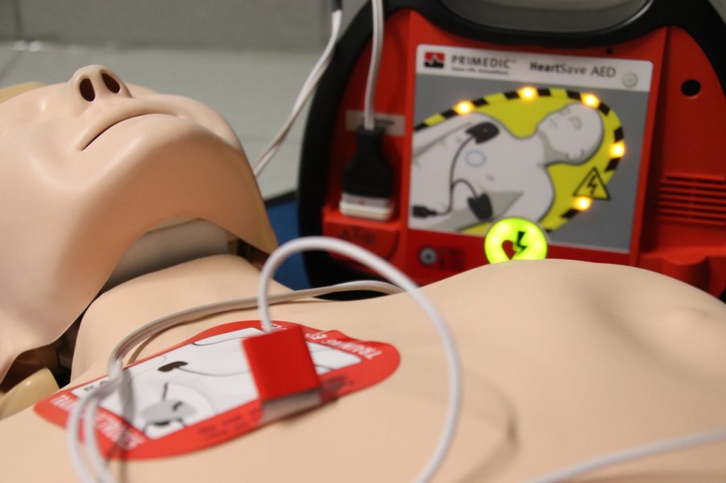 An AED is placed right beside a dummy for CPR training and practice