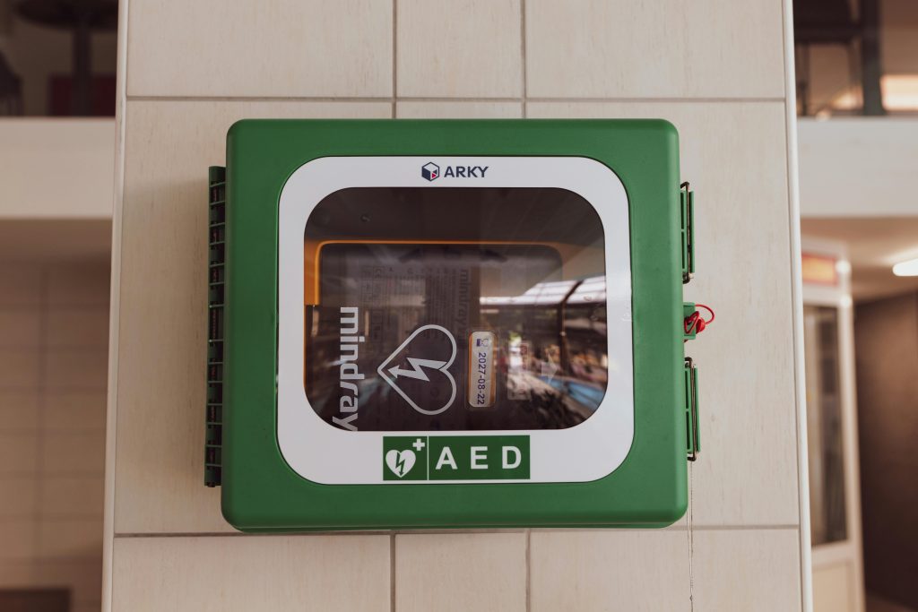 In a green box mounted on a tiled pillar, an AED is ready in a public place