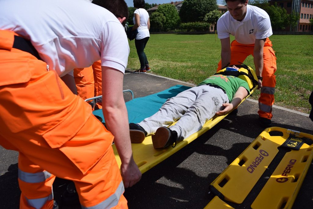 A group of individuals are being trained in emergency preparedness by lifting a person on a gurney