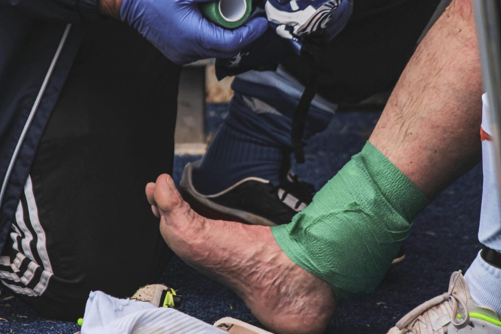 A football player is being treated with green bandages by an EMT