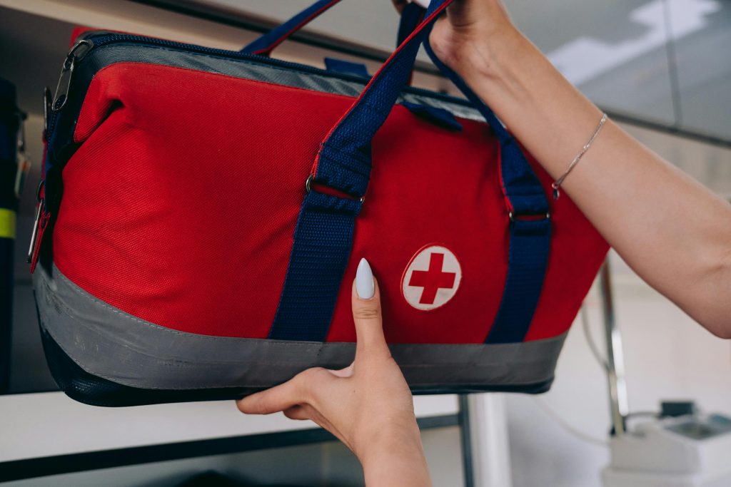 A person is getting their emergency supplies from a shelf which are in a red duffle bag