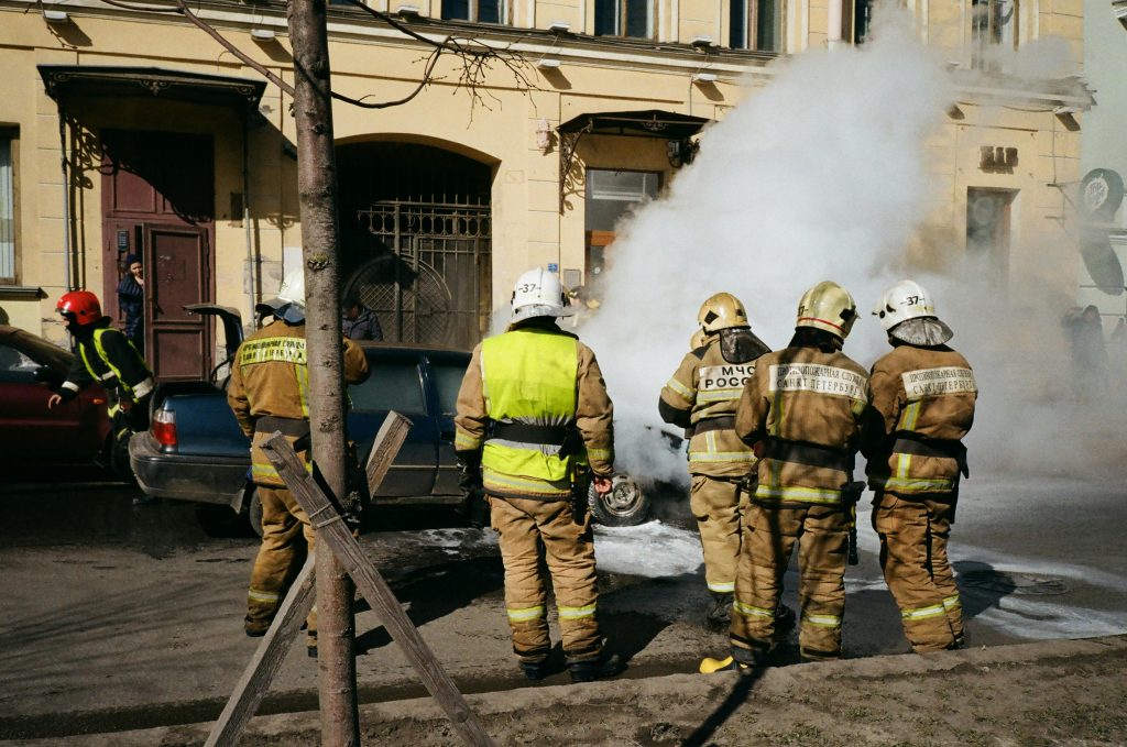 A group of emergency first responders standing by the side as they help extinguish a fire with water