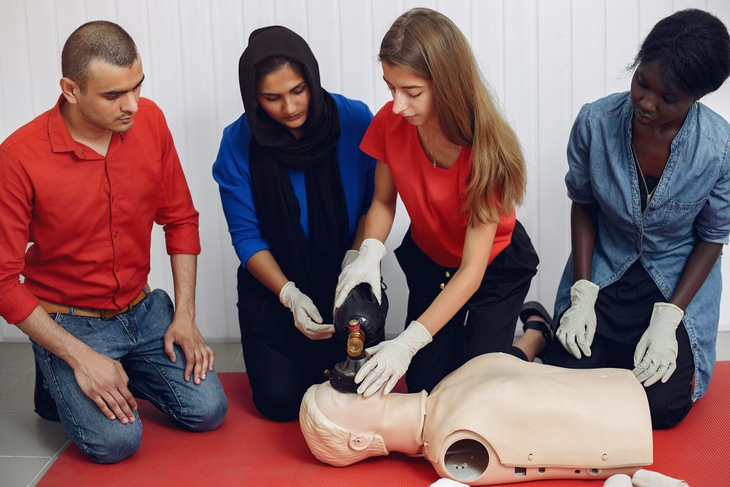 A group of people are training for first aid as the first session of their emergency preparedness training using a CPR dummy