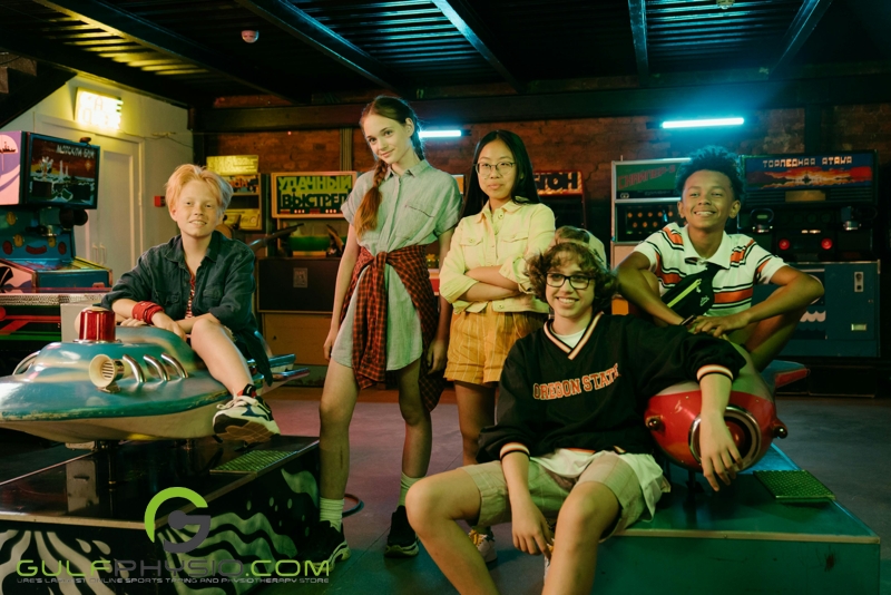 A group of teenagers smiling and posing for the camera while in an arcade.