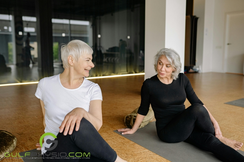 Two older women chatting happily as they practice yoga.