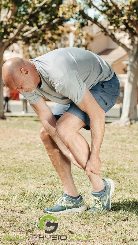 A man clutches his injured ankle, his face contorted in pain.