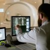 A doctor examines an ongoing MRI scan of a patient.