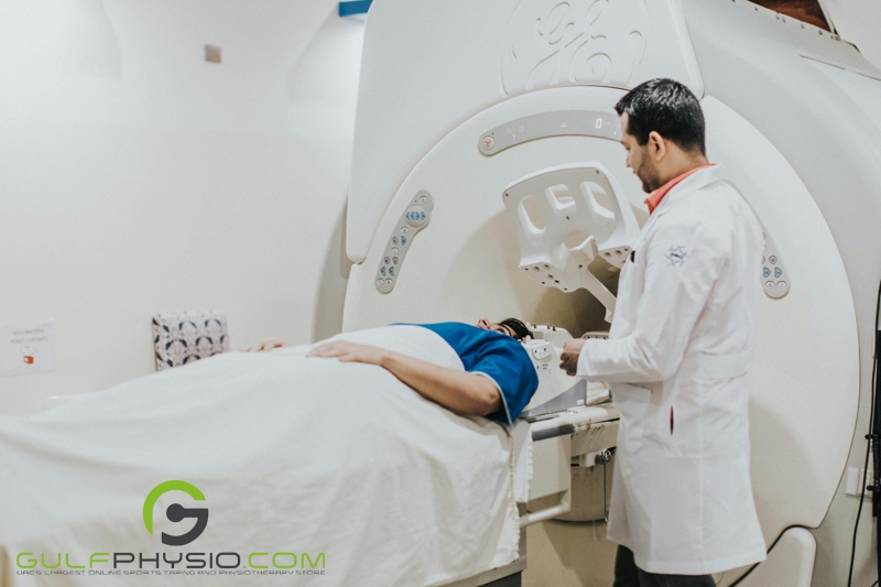  A doctor talking to a patient who is about to enter an MRI Machine. The patient is lying on the patient's table