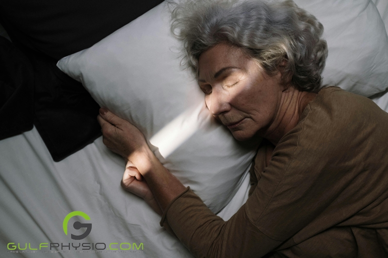 An older woman peacefully asleep in her bed.